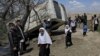 FILE - Schoolgirls walk past a damaged minibus after it was hit by a bomb blast in the Bagrami district of Kabul, Afghanistan.