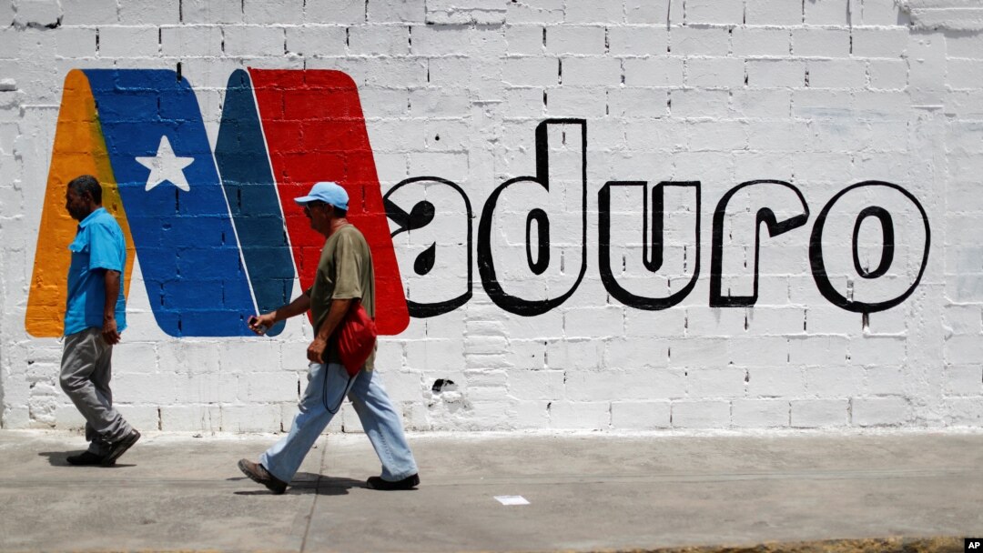 Supporters of Venezuela's President Nicolas Maduro walk past a campaign mural before a rally with him, in Charallave, Venezuela, May 15, 2018.