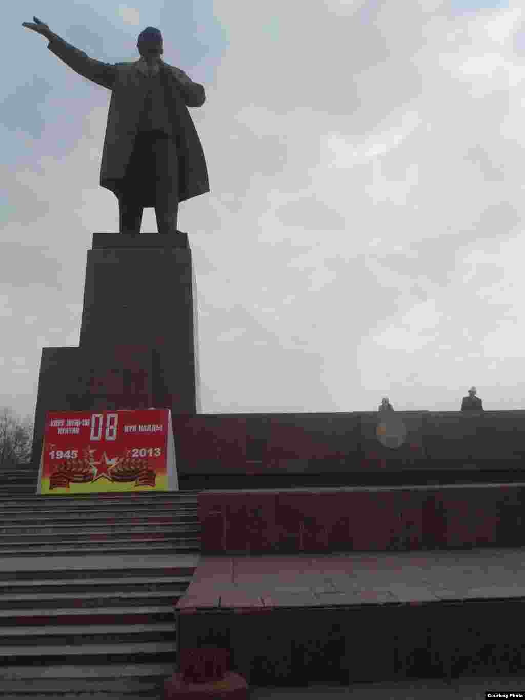 Lenin haykali maydondan o'tayotgan ishchilarga qarata xitob qilayotgandek.
