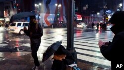 FILE - People walk by a homeless man panhandling on a New York sidewalk, Jan. 24, 2017.
