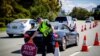 FILE - A Queensland police officer moves a stop sign at a vehicle checkpoint on the Pacific Highway on the Queensland - New South Wales border, in Brisbane on April 15, 2020. 