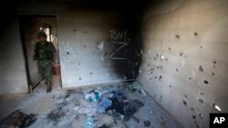 FILE - In this Sept. 6, 2014 file photo, a soldier enters a bullet-riddled home, tagged with the initials CDG for the Gulf Cartel, and Z for Zetas, in Ciudad Victoria, in Mexico's state of Tamaulipas. 