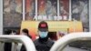 世界卫生组织团队于 2021年1月30日星期六抵达中国中部湖北省武汉市举行的抗击冠状病毒展览后，一名戴着口罩和带有中国国旗的帽子的保安人员守卫入口。