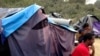 FILE - People sit by a tent at a makeshift camp in Calais, northern France, Sept. 7, 2014.