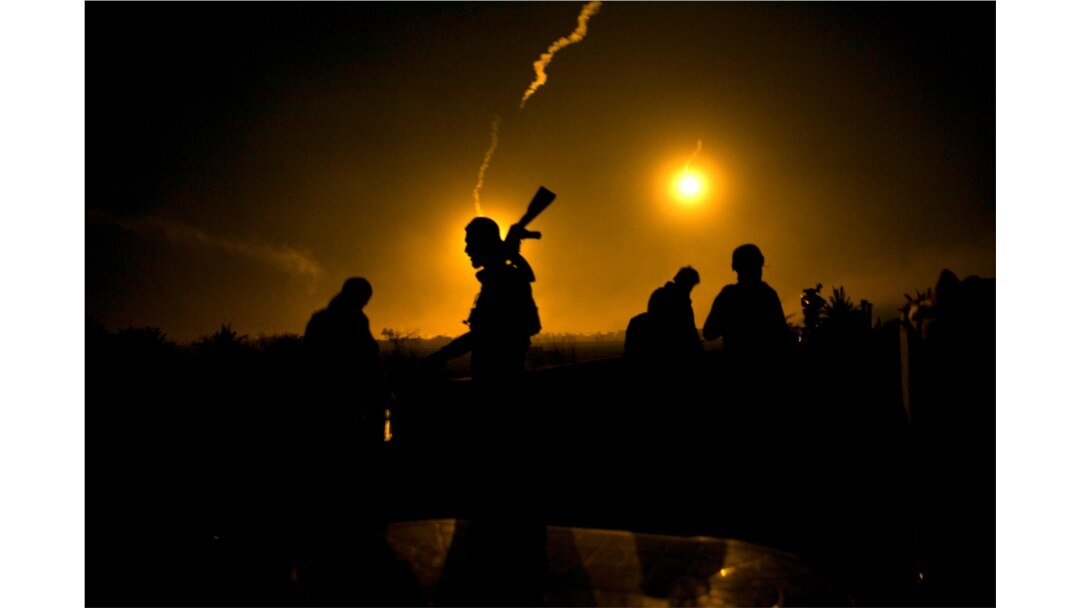 FILE - Syrian Democratic Forces fighters watch illumination rounds light up Baghuz, Syria, as the last pocket of Islamic State militants is attacked, March 12, 2019.