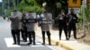 FILE - Nicaraguan police officers block journalists working outside the house of opposition leader Cristiana Chamorro after prosecutors sought her arrest for money laundering and other crimes, in Managua, Nicaragua, June 2, 2021.