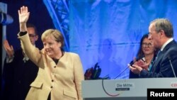 German Chancellor Angela Merkel waves next to Christian Democratic Union (CDU) leader and top candidate for chancellor Armin Laschet during his election rally in Stralsund, Germany, Sept. 21, 2021. 