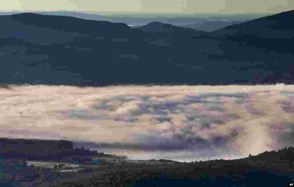 A billowy layer of fog hovers over Webb Lake on a chilly morning where the temperature dropped into the mid-40s in Weld, Maine, USA.