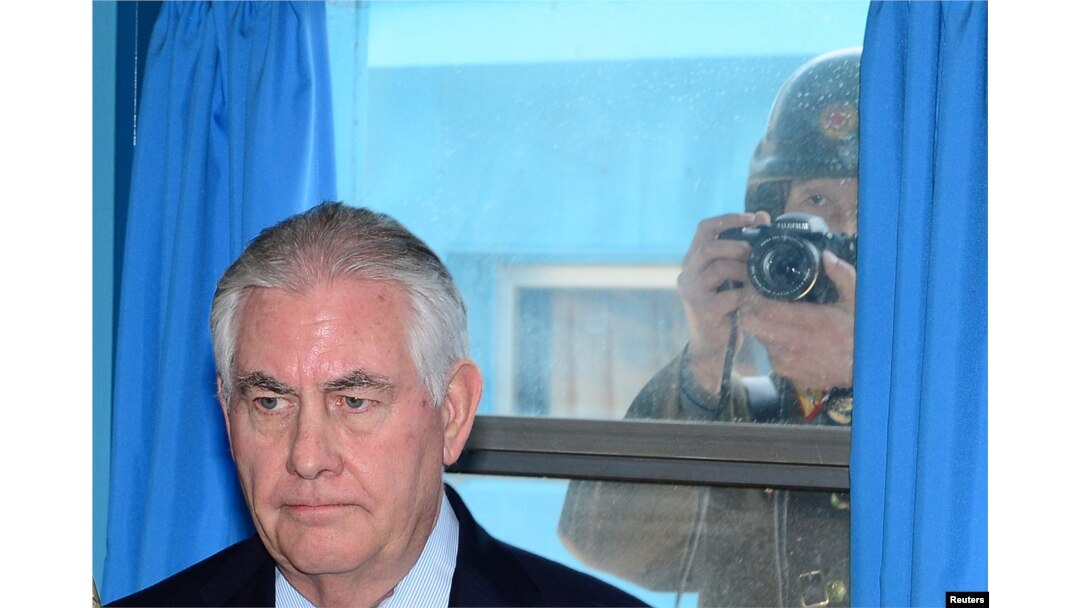 U.S. Secretary of State Rex Tillerson is briefed by U.S. Gen. Vincent K. Brooks, commander of the United Nations Command, Combined Forces Command and United States Forces Korea (not pictured), as a North Korean soldier takes a photograph through a window