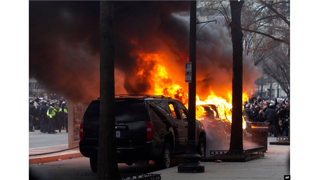 FILE - Demonstrators torch a car during the demonstration in downtown Washington, Jan. 20, 2017, during the inauguration of President Donald Trump.