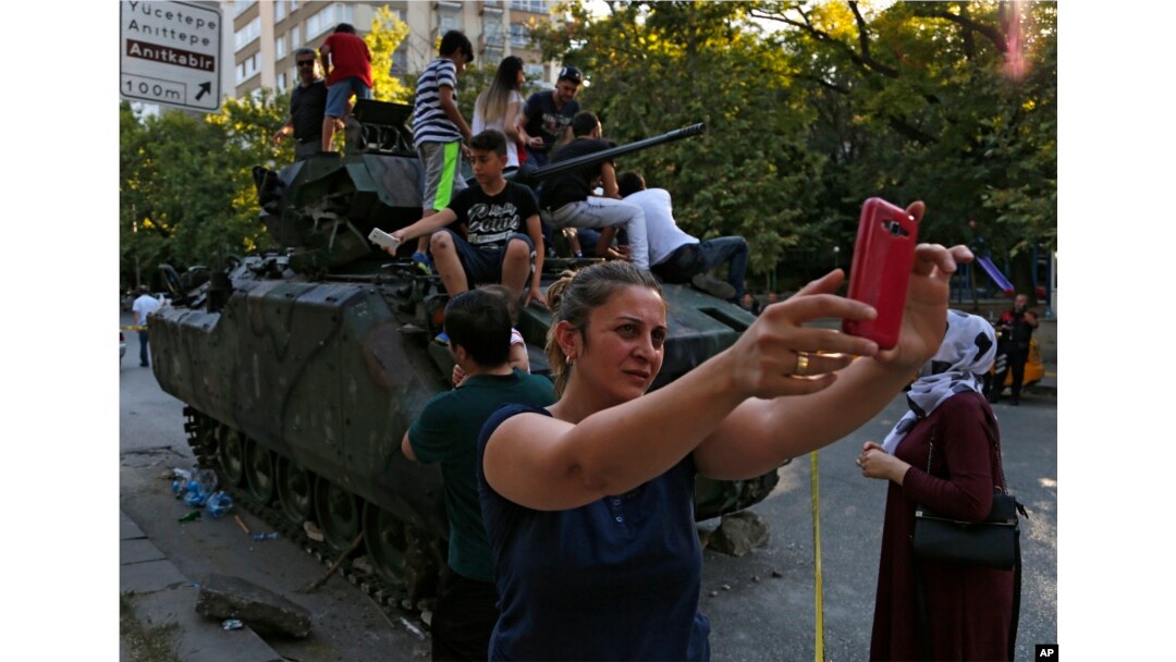 A woman takes a selfie in front a damaged Turkish military armored personnel carrier that was attacked by protesters near the Turkish military headquarters in Ankara, July 16, 2016.