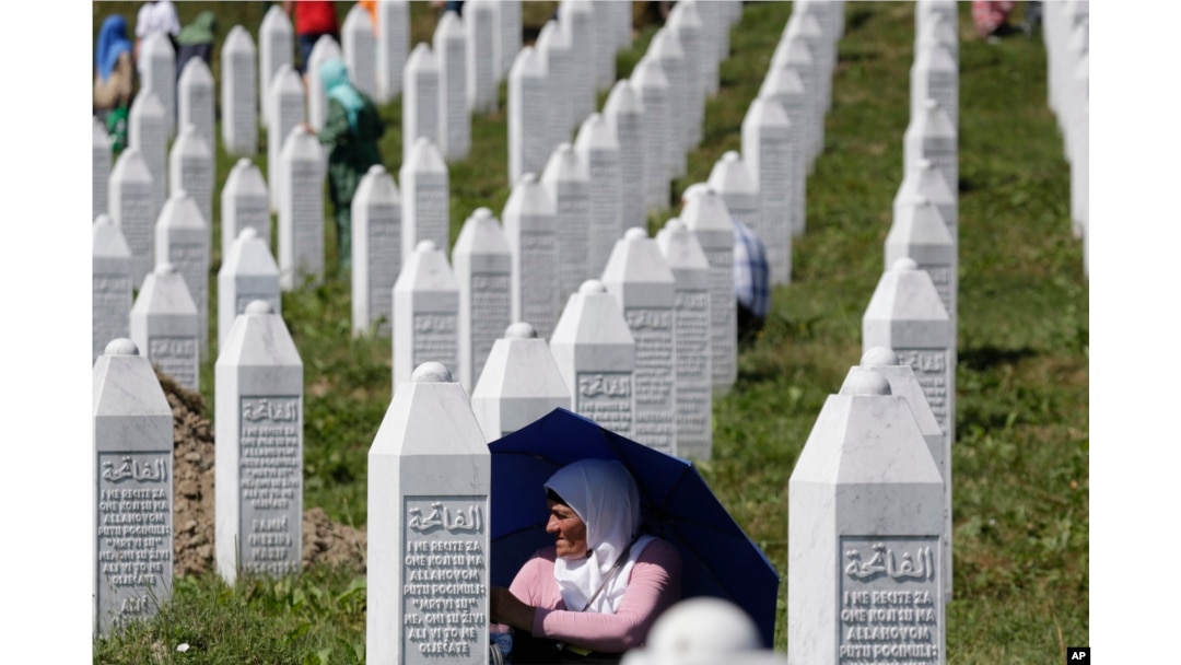 FILE - A Bosnian Muslim woman protects herself from the sun during a funeral ceremony for dozens of newly identified victims of the 1995 Srebrenica massacre, at the memorial center of Potocari, near Srebrenica, 150 kms northeast of Sarajevo, Bosnia, July 11, 2017.