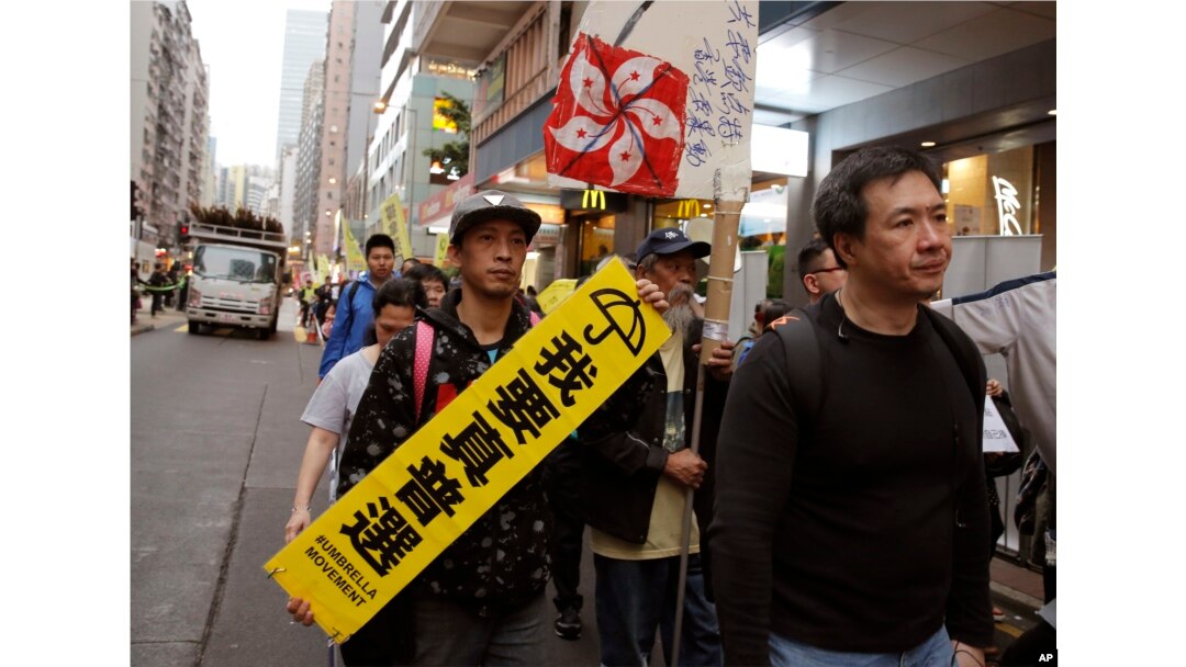 Pro-democracy protesters carry a sign reading "I want genuine universal suffrage" and a Hong Kong national flag during a demonstration in Hong Kong, March 25, 2017.