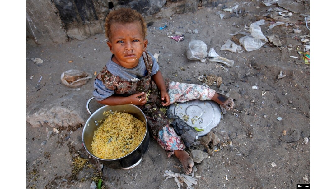 FILE - A girl displaced by the war in the northwestern areas of Yemen eats outside her family's makeshift hut on a street in the Red Sea port city of Hodeida, Yemen, Dec. 25, 2017.