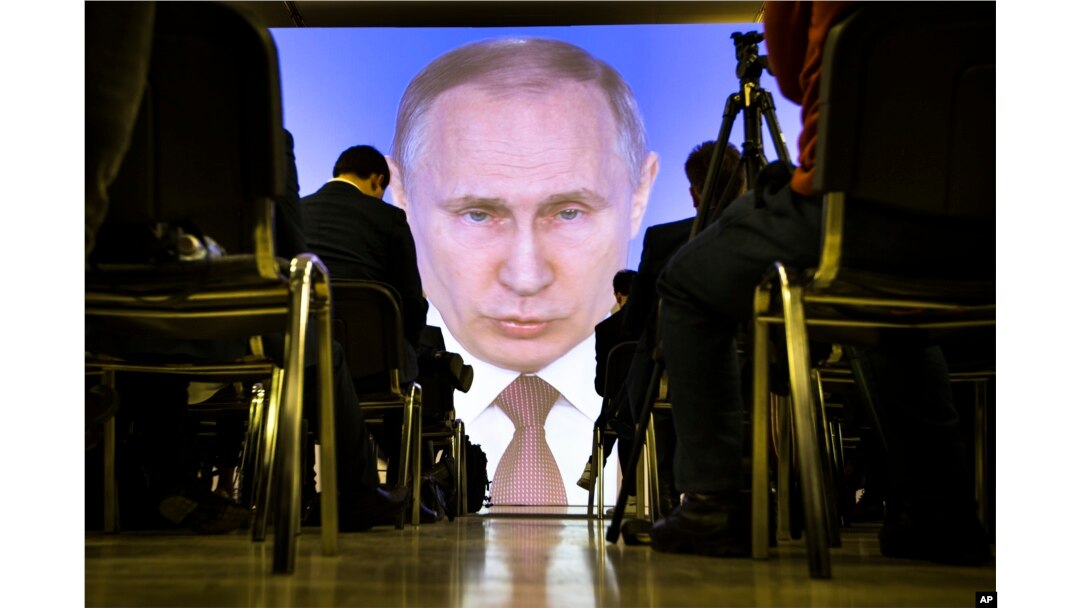 FILE - Journalists watch as Russian President Vladimir Putin gives his annual state of the nation address in Manezh in Moscow, March 1, 2018.