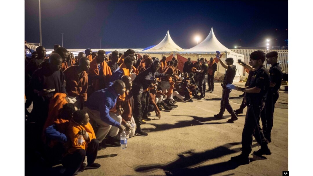 FILE - A group of migrants react in front of Spanish Police officers at the port of Algeciras, southern Spain, after being rescued by Spain's Maritime Rescue Service in the Strait of Gibraltar, July 31, 2018.
