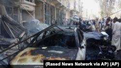 People gather around the rubble of building and destroyed vehicles after an airstrike in Al-Bab on the outskirts of Aleppo, Syria, Oct. 5, 2015, in a photo released by Rased News Network, which is affiliated with Islamic State militants.