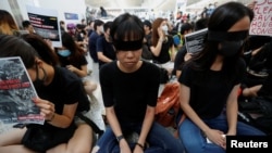 香港反送中示威者2019年8月12日在香港国际机场静坐示威时用黑布蒙眼，抗议警方一天前与示威者的冲突中使一名抗议者眼睛受伤。