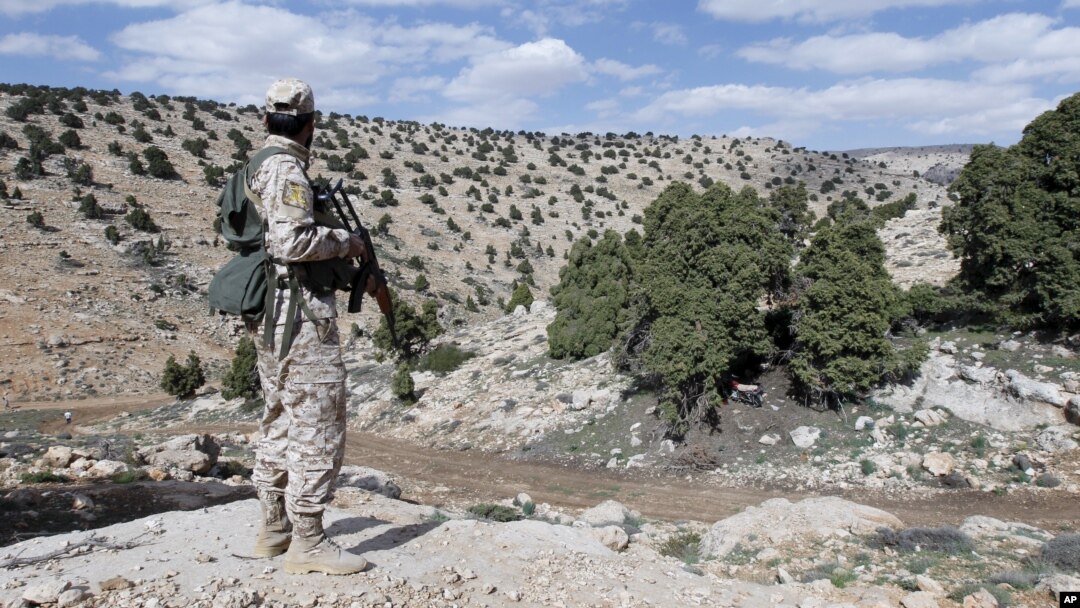 FILE - A Lebanon Hezbollah fighter carries his weapon as he stands in Khashaat, in the Qalamoun region after they advanced in the area, May 15, 2015. 
