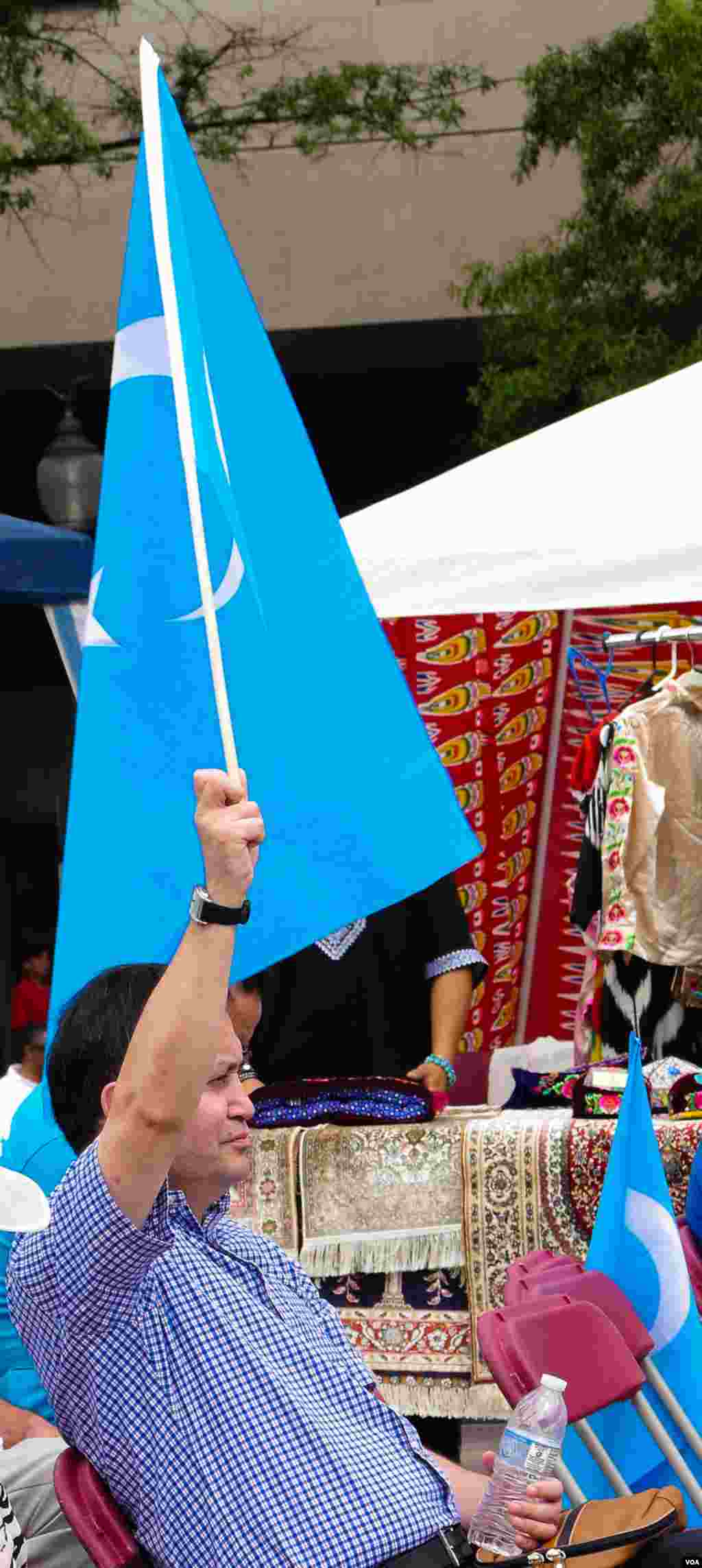Vashingtonda Uyg'ur madaniy festivali. Uyg'ur-Amerika uyushmasi prezidenti Olim Seytoff Sharqiy Turkiston bayrog'ini ko'tarib turibdi, Vashington, 3-avgust, 2014-yil. Odil Ruzaliev surati
