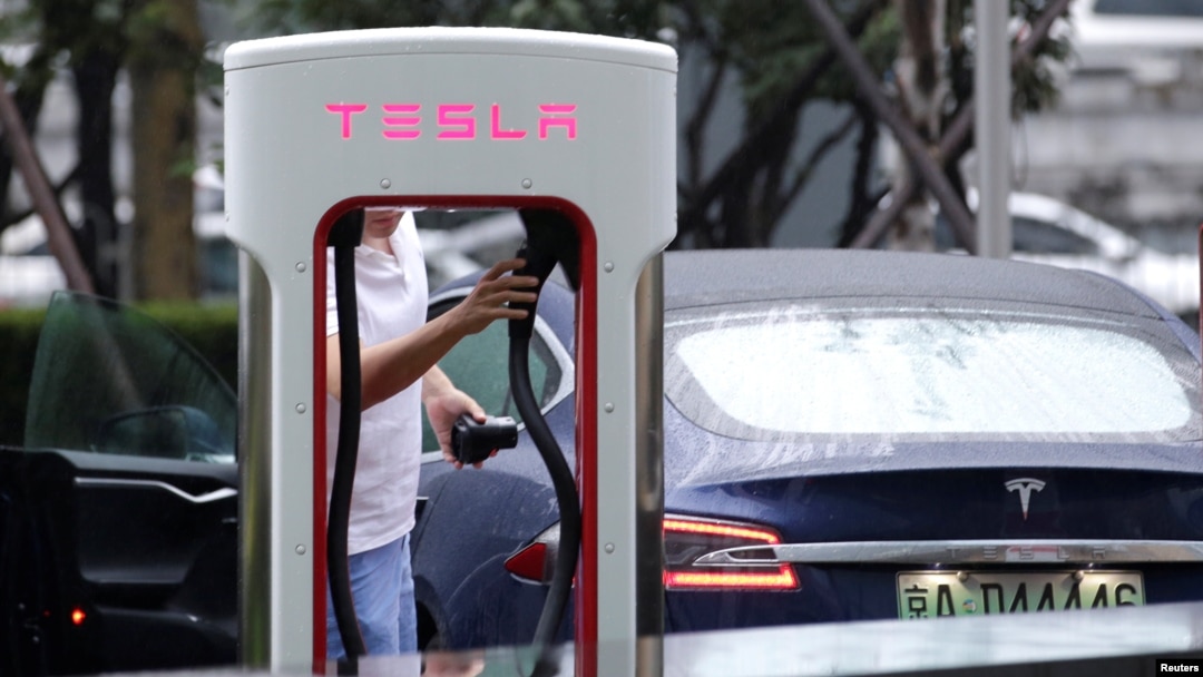 FILE - A man finishes to charge his Tesla car at a charging station in Beijing, China, July 11, 2018.