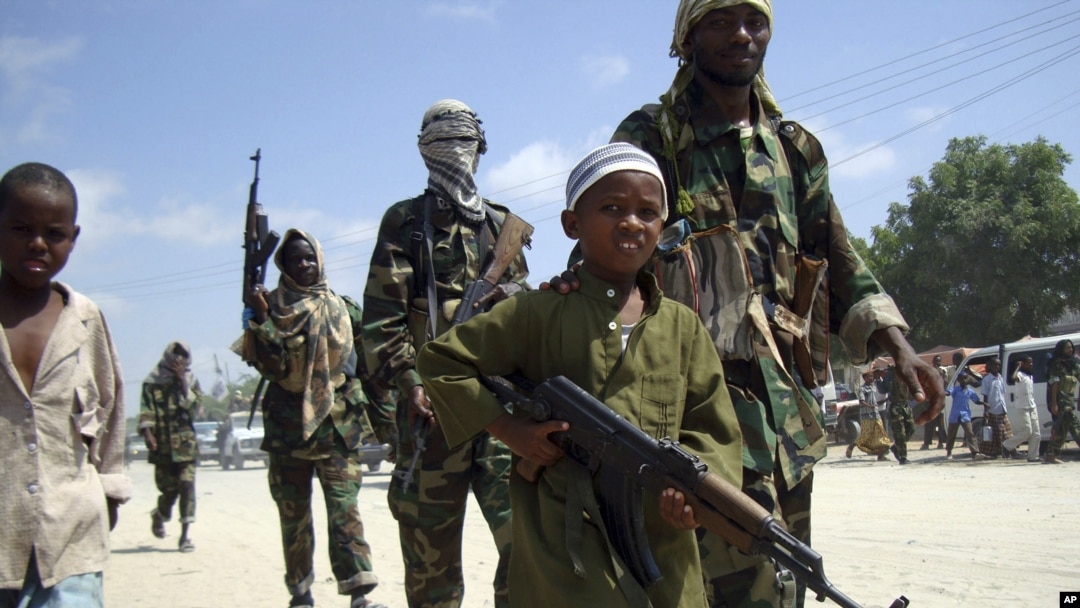 FILE - A young boy leads hard-line Islamist al-Shabab fighters as they conduct military exercises in northern Mogadishu's Suqaholaha neighborhood, Somalia.