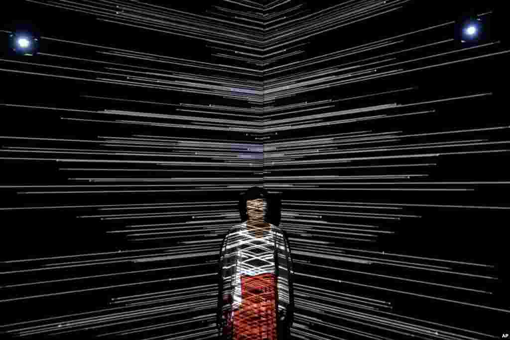A woman is beamed by light at an art installation titled "Infinity Room" displayed during The Future of Today Exhibition at Today Art Museum in Beijing, China.