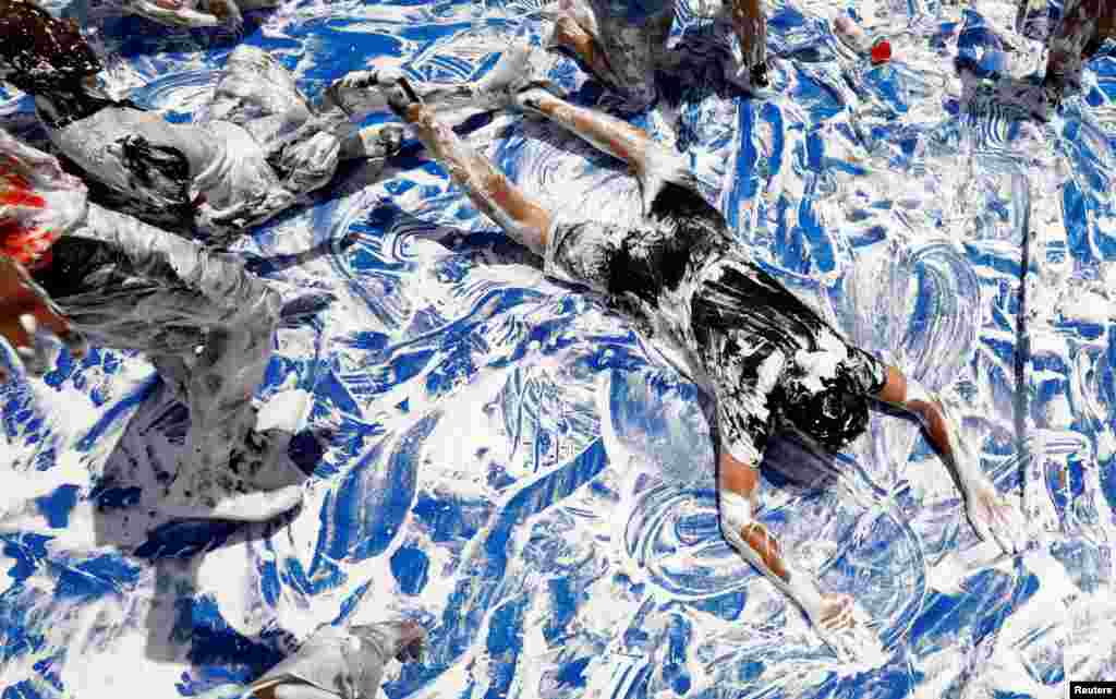 Children cool off with a makeshift slip-n-side of water and shaving cream while attending the Don Bosco Center's summer program for at-risk middle school children in Manassas, Virginia.