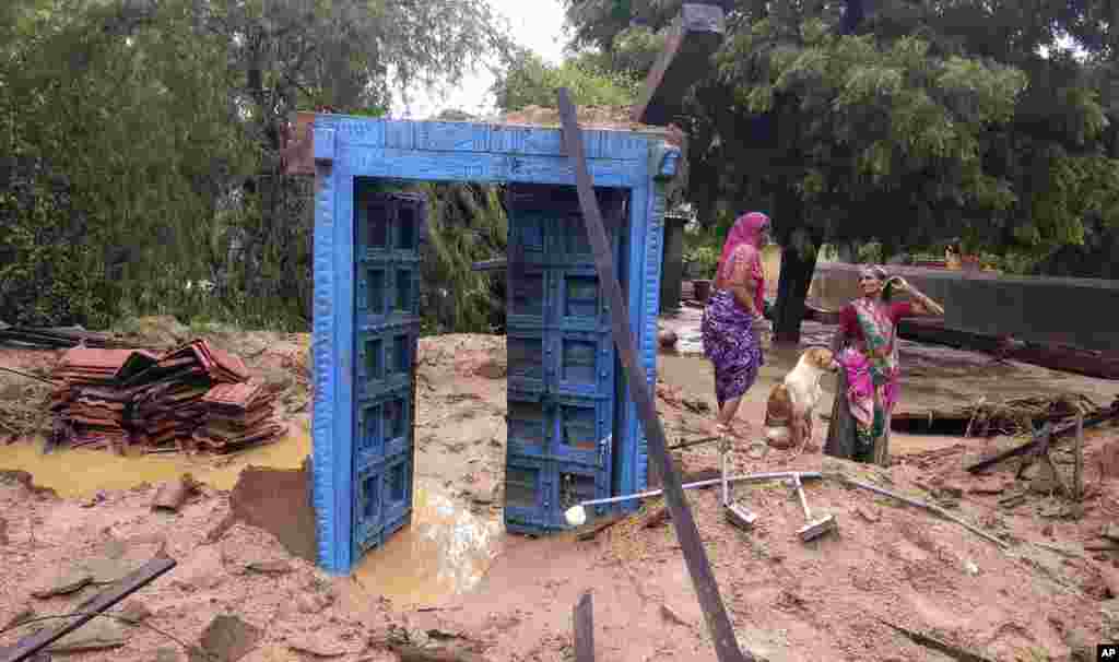 Village women stand next to flood debris in Runi village near Thara in Banaskantha district, Gujarat, India.