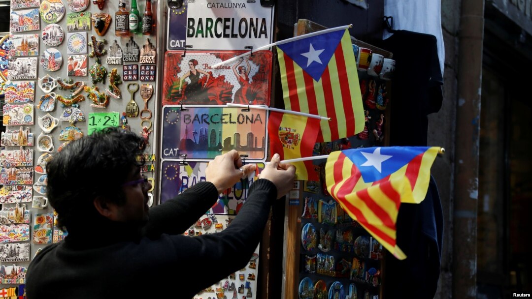 A shop keeper displays Catalan separatist "Estelada" flags next to souvenirs for tourists at a shop in Barcelona, Dec. 22, 2017. 