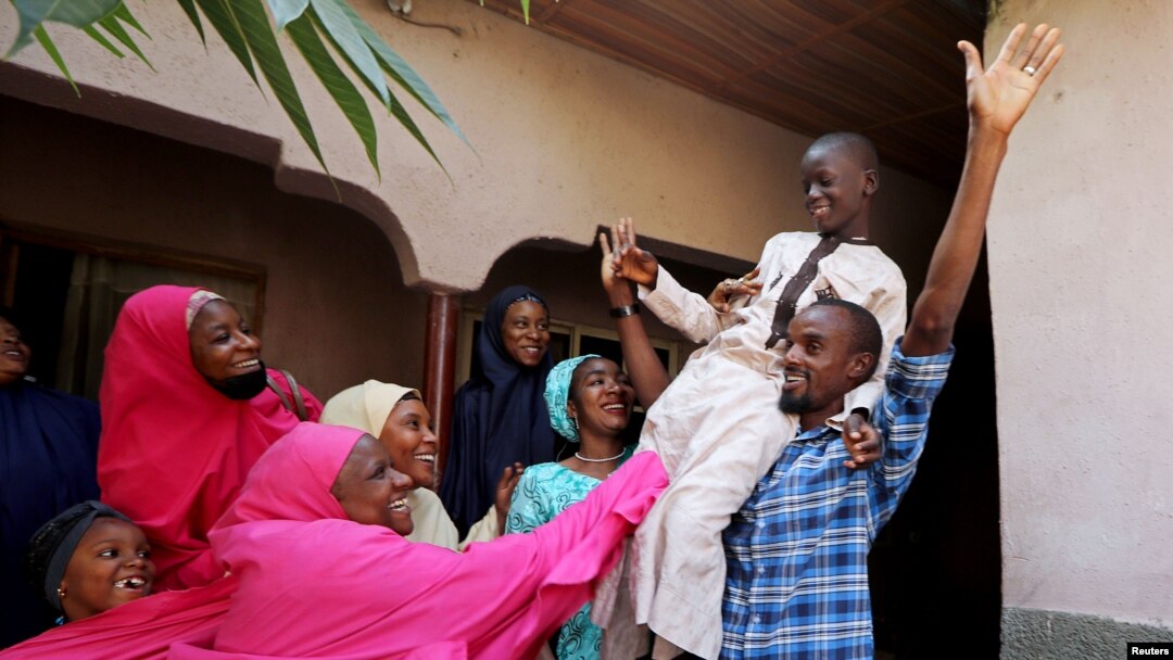 FILE - Muhammed Bello, a rescued student, is carried by his father as his relatives celebrate after he retuned home in Kankara, Nigeria, Dec. 19, 2020. 