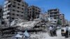 People stand in front of damaged buildings in the town of Douma, the site of a suspected chemical weapons attack, near Damascus, Syria, April 16, 2018. 