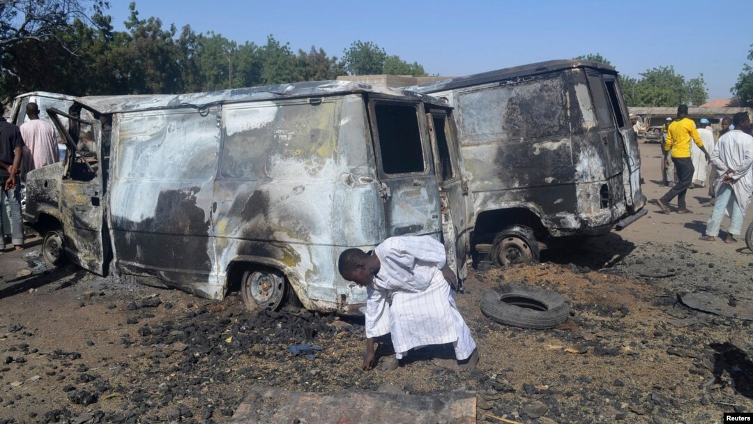 A boy searches the ground next to a burnt-out vehicle, caused by an attack by Boko Haram militants in Bama, Borno State, February 20, 2014.