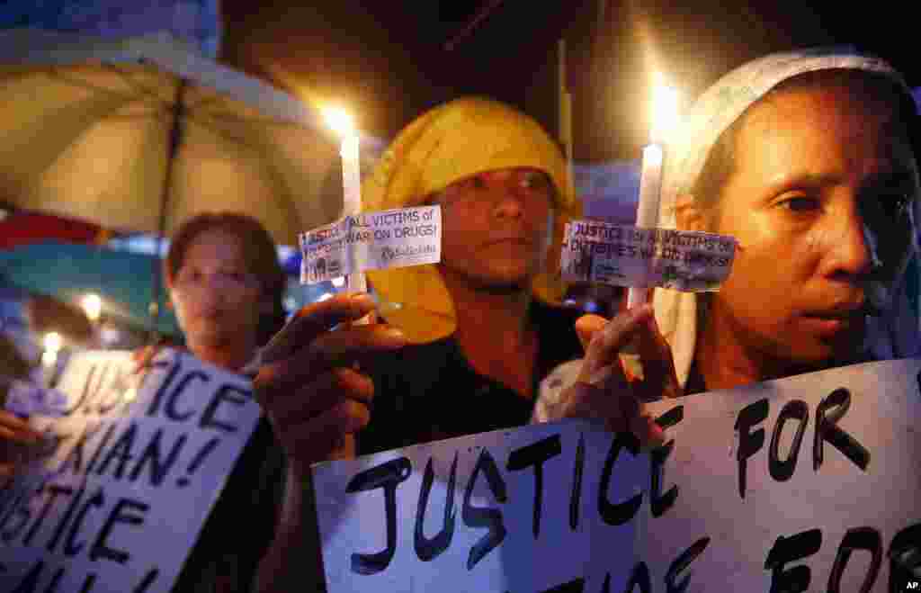 Protesters display placards and light candles during a rally to denounce the killing of Kian Loyd delos Santos, a 17-year-old Grade 11 student by police in Quezon city northeast of Manila, Philippines.