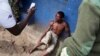 Jean Claude Niyonzima, a suspected member of the ruling party's Imbonerakure youth militia, sits under soldiers' protection from a mob of demonstrators after he came out of hiding in a sewer in the Cibitoke district of Bujumbura, Burundi, May 7, 2015. 