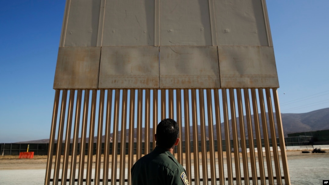 FILE - A U.S. Border Patrol agent looks at one of border wall prototypes in San Diego, June 28, 2018. 