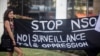 FILE - A protester holds a banner during a protest attended by about a dozen people outside the offices of the Israeli cyber firm NSO Group in Herzliya near Tel Aviv, Israel, July 25, 2021.