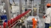 FILE - A person works with robots at Procter & Gamble's factory in Tabler Station, West Virginia, U.S., May 28, 2021. 