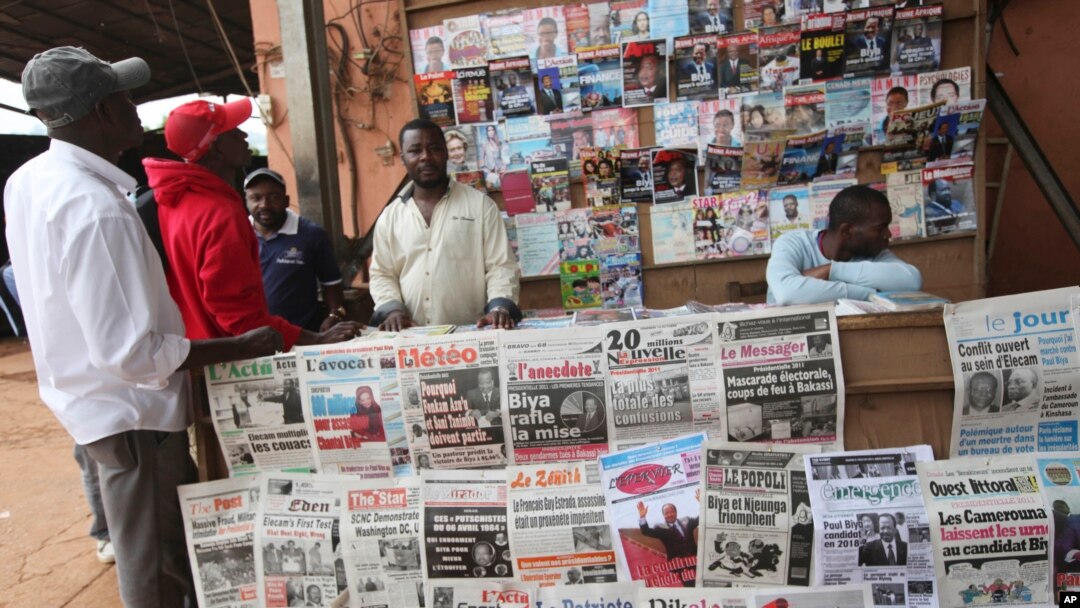 FILE - People look over local newspapers in Yaounde, Cameroon. Cameroon has suspended 16 journalists and seven news outlets for what it calls media offenses. 