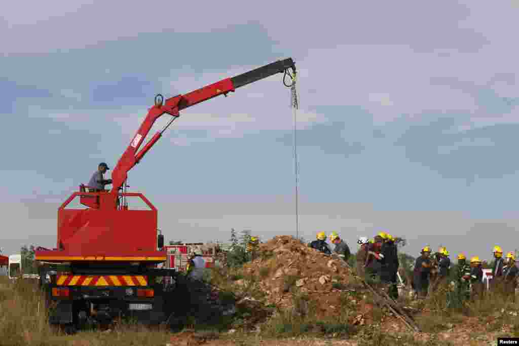 Rescue officials use a crane to remove debris as they work to rescue trapped suspected illegal miners from an abandoned gold shaft in Benoni, east of Johannesburg, South Africa, Feb. 16, 2014.