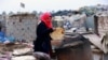 Umm Salem bakes bread in front of her hut at an encampment for the displaced outside Baghdad, Iraq, Feb. 12, 2018. 