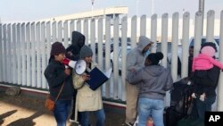 FILE - In this Nov. 12, 2019, photo, volunteers call names of people on a waiting list trying to obtain asylum in the United States along the U.S.-Mexico border in Tijuana, Mexico. 