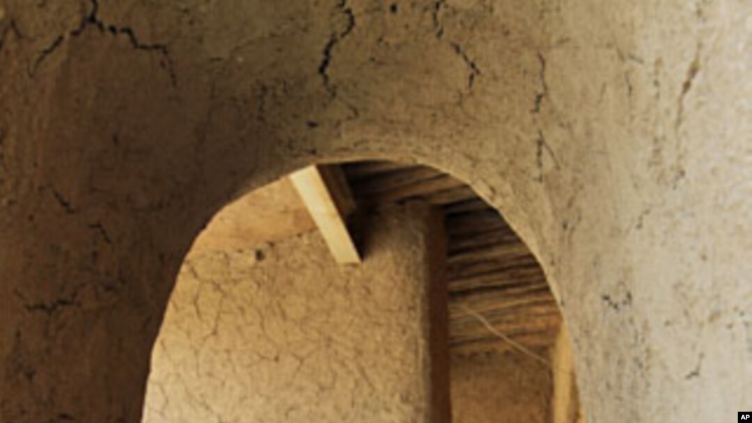 A man uses his mobile phone as he stands at the entrance of his house in Agadez, northern Niger, September 10, 2011