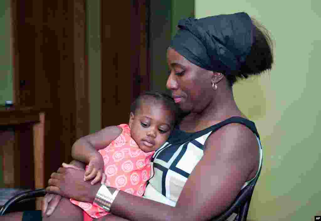Liberiya hukumati rasmiysi sifatida Nigeriyaga kelib ishlagan, ayni paytda AQSh fuqarosi bo'lgan Patrik Soyerning xotini Dekonti Soyer bir yoshli farzandi bilan, Minnesota, 29-iyul, 2014-yil.