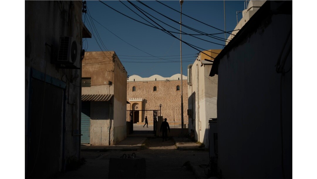 FILE - People walk outside a mosque in Tripoli, Libya, on Feb. 27, 2020. Eastern-based opposition forces attacked Tripoli last spring to wrest it from control of the weak U.N.-backed government. The fierce fighting has killed hundreds of civilians.