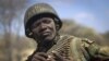 A Kenyan army soldier wears a helmet on which is written in Kiswahili "Tea in Kismayo", referring to a key strategic Somali town then under the control of al-Shabab, checks his ammunition belt near the town of Dhobley, in Somalia.
