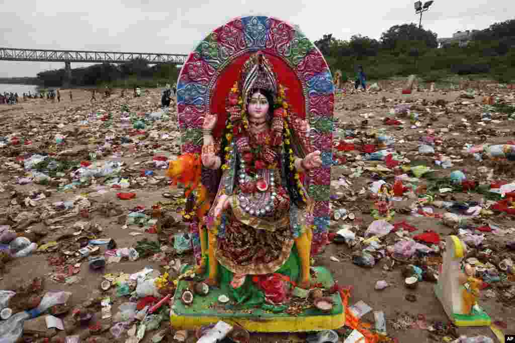 An idol of Hindu goddess Dashama stands among offerings and worship materials on the bank of river Sabarmati after the end of Dashama festival in Ahmadabad, India.