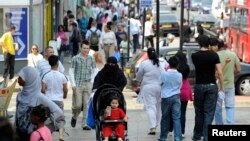 FILE - Shoppers walk in a market in Upton Park, a neighborhood in the British capital's most culturally diverse borough of Newham, in east London June 26, 2010. 