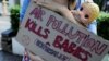 FILE - An environmental activist carrying a doll holds a placard outside the Central Jakarta Court in Jakarta, Indonesia, September 16, 2021.