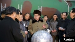 김정은 북한 국방위원회 제1위원장이 핵무기 연구 부문 과학자, 기술자들을 만나 핵무기 병기화 사업을 지도하는 모습을 지난 2016년 3월 조선중앙통신이 보도했다. 사진 아래쪽에 핵탄두 기폭장치 추정 물체가 보인다. 